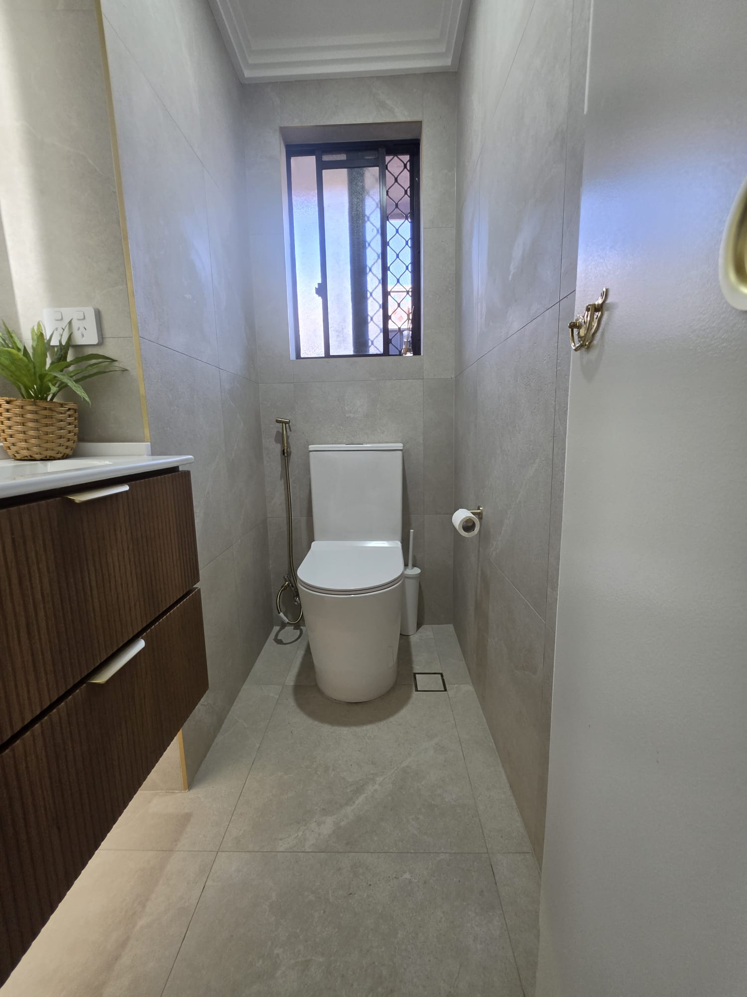 Completed bathroom with large format grey stone tiles and timber vanity
